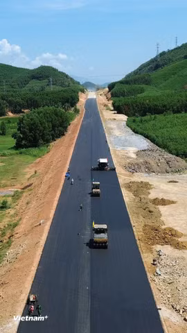 Nhà thầu thi công thảm bê tông nhựa nền đường dự án cao tốc. (Ảnh: Khánh Hùng/Vietnam+)