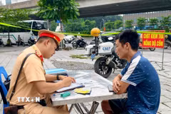 Cảnh sát giao thông lập biên bản đối với trường hợp vi phạm quy định trong hoạt động kinh doanh vận tải. (Ảnh: Trung Nguyên/TTXVN)