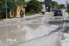Người và phương tiện vất vả đi qua Quốc lộ 30 đoạn thuộc địa bàn ấp Gò Da, xã Tân Hồng (tỉnh Đồng Tháp). (Ảnh: Nhựt An/TTXVN)