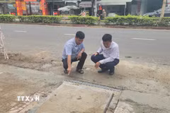 Đại diện đơn vị thi công và tư vấn giám sát kiểm tra vị trí hố thu nước trên tuyến đường Phú Riềng Đỏ, phường Bình Phước, thành phố Đồng Nai. (Ảnh: Đậu Tất Thành/TTXVN)