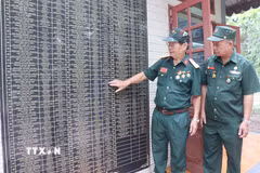 Cựu chiến binh Vũ Đức Ninh cùng đồng đội xem lại tên những người đồng đội đã mất trong chiến tranh được khắc tên trang trọng tại nhà bia tưởng niệm tại phường Hố Nai, thành phố Đồng Nai. (Ảnh: Lê Xuân/TTXVN)