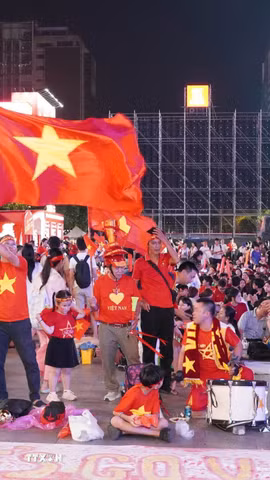 Người hâm mộ với cờ đỏ sao vàng, trống và kèn tập trung tại phố đi bộ Nguyễn Huệ, sẵn sàng tiếp lửa cho đội tuyển Việt Nam trong trận chung kết lượt đi ASEAN Hyundai Cup 2026 gặp Thái Lan. (Ảnh: Trung Tuyến/TTXVN)