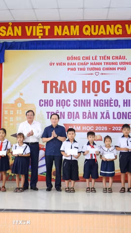 Các học sinh nghèo, hiếu học tại xã Long Chữ, tỉnh Tây Ninh nhận học bổng từ Phó Thủ tướng Chính phủ Lê Tiến Châu (phải) và Chủ tịch UBND tỉnh Tây Ninh Lê Văn Hẳn (trái). (Ảnh: Giang Phương/TTXVN)