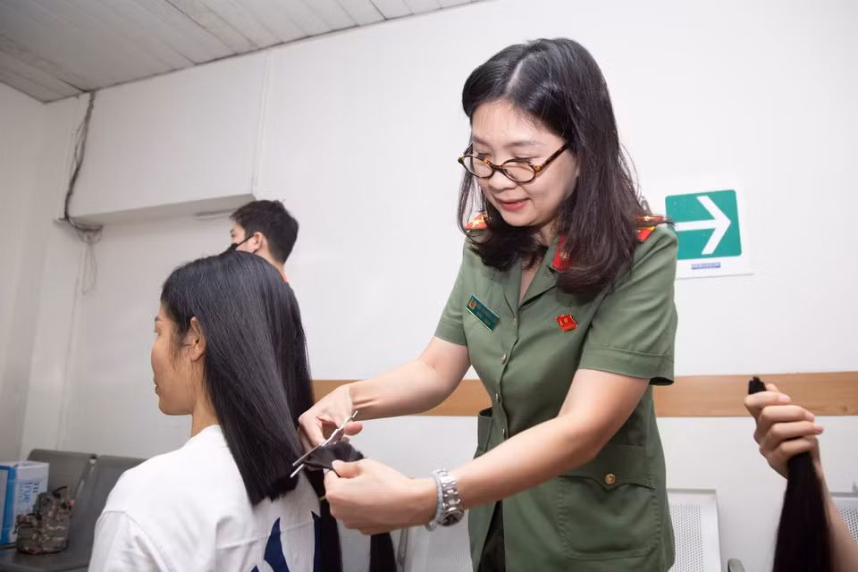 Sau lưng mỗi người hiến tóc là một cán bộ, chiến sỹ Công an Hà Nội, tay cầm lược, tay cầm kéo. (Ảnh: PV/Vietnam+)