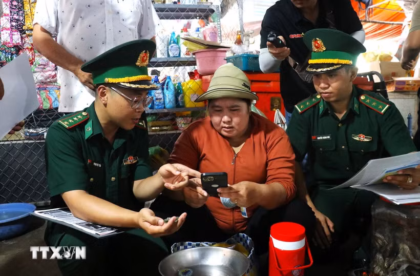 Chiến sỹ Đồn Biên phòng Cửa khẩu Mỹ Quý Tây (Tây Ninh) tuyên truyền pháp luật cho người dân tại khu vực chợ Tho Mo, đưa những quy định về biên giới, phòng, chống tội phạm đến gần hơn với đời sống. (Ảnh: Bùi Giang/TTXVN)