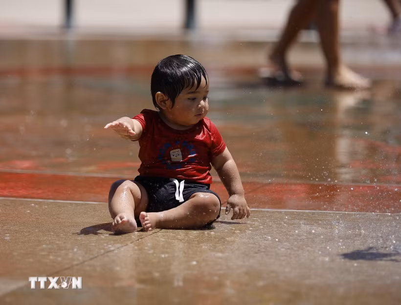Em nhỏ tránh nóng bên đài phun nước ở Los Angeles, California, Mỹ. (Ảnh: THX/TTXVN phát)