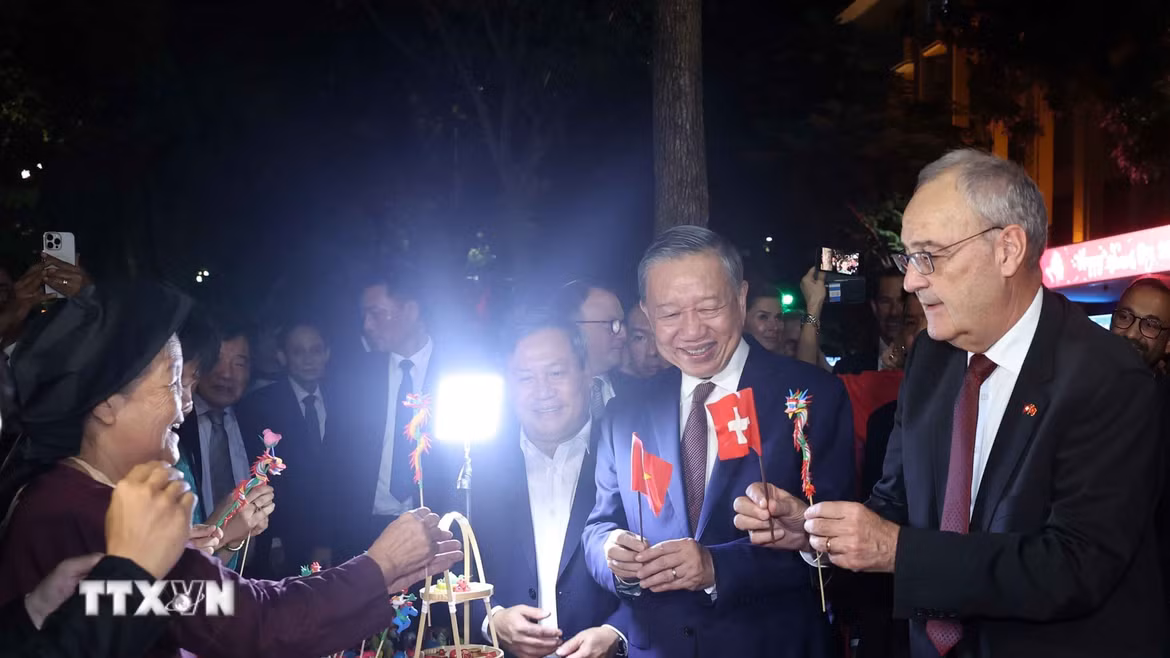 Tổng thống Thụy Sĩ Guy Parmelin bày tỏ sự thích thú với sản phẩm tò he của những nghệ nhân làng Xuân La - nét văn hóa dân gian Việt Nam độc đáo trên phố đi bộ hồ Hoàn Kiếm. (Ảnh: Thống Nhất/TTXVN)