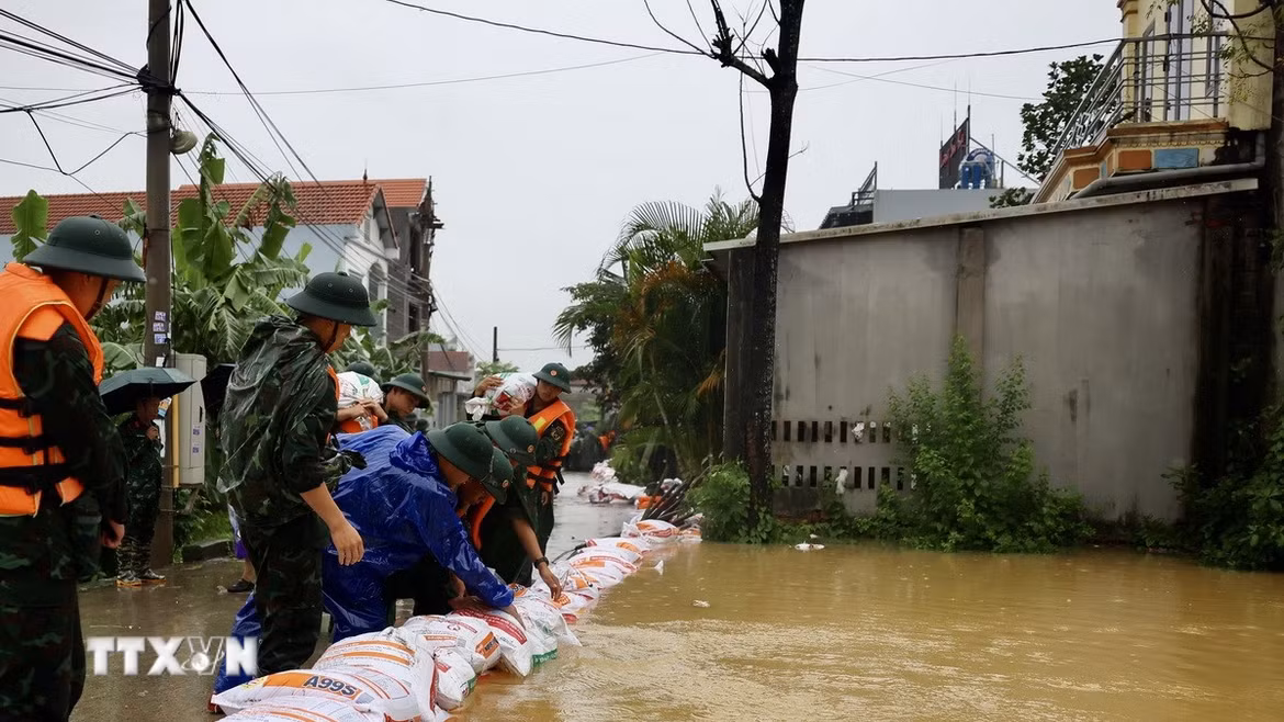 Lực lượng bộ đội hỗ trợ đắp đê bao ngăn nước khu dân cư ven sông Bùi. (Ảnh: Nhật Anh/TTXVN)