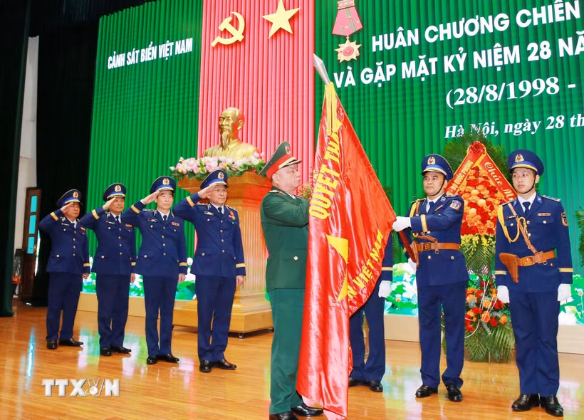 Thượng tướng Nguyễn Quang Ngọc, Ủy viên Trung ương Đảng, Thứ trưởng Bộ Quốc phòng gắn Huân chương Chiến công hạng Nhất lên Quân kỳ Quyết thắng của Cảnh sát biển Việt Nam. (Ảnh: Trọng Đức/TTXVN)
