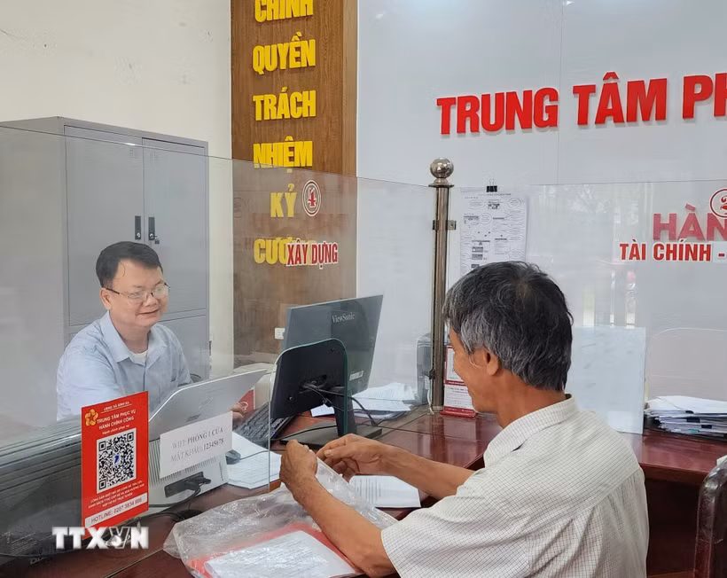 Công chức phường Mạo Khê, Quảng Ninh, hướng dẫn công dân nộp hồ sơ chứng thực lên Cổng dịch vụ công Quốc gia. (Ảnh: Thanh Vân/TTXVN)