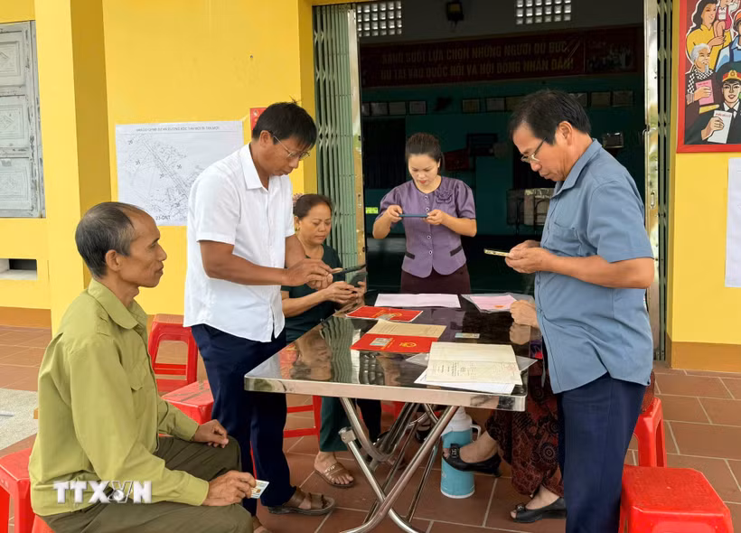 Cán bộ hướng dẫn người dân cung cấp thông tin, hồ sơ phục vụ cập nhật dữ liệu đất đai. (Ảnh: Đồng Thúy/TTXVN)
