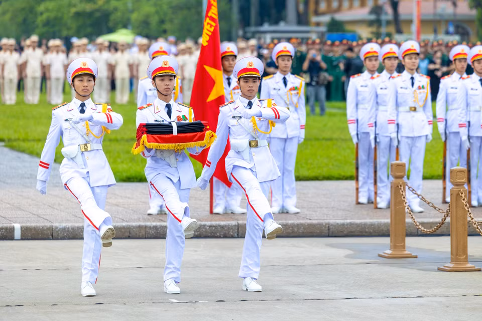 Quốc kỳ được các chiến sĩ buộc thêm dải băng đen theo đúng nghi thức. (Ảnh: Minh Sơn/Vietnam+)