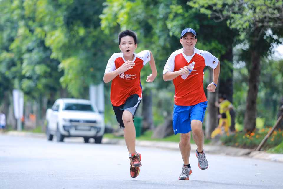 Hai bố con chạy thi với nhau xem ai về đích trước. (Ảnh: Minh Sơn/Vietnam+)