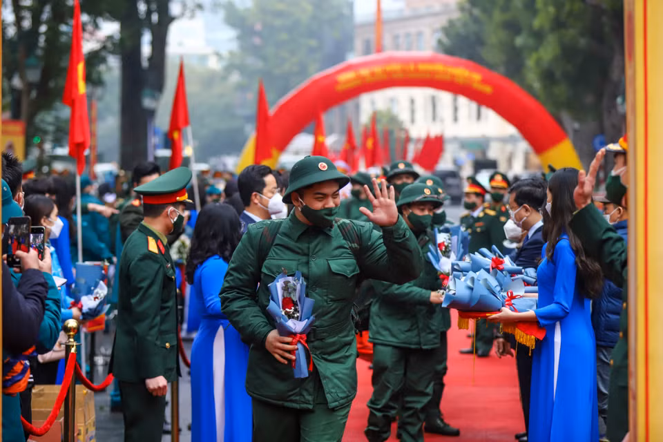 Tân binh bước qua cổng vinh quang để lên đường tham gia nghĩa vụ quân sự. Nhiều tân binh tặng lại hoa cho người thân. (Ảnh: Minh Sơn/Vietnam+)