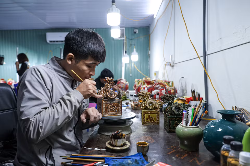 Sau khi được tráng men và nung thành phẩm trong vòng 5 ngày, sản phẩm sẽ được mang đi vẽ vàng. Các họa tiết của Kỳ Linh Giáp Thìn 2024 được vẽ tay bởi hàng ngàn nét vẽ bằng vàng ròng tạo ra tác phẩm độc đáo. (Ảnh: Minh Sơn/Vietnam+)
