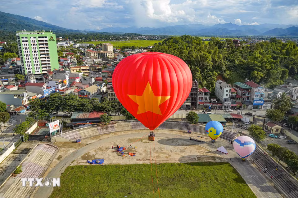 Khinh khí cầu mang hình ảnh Quốc kỳ Việt Nam nổi bật giữa nền trời xanh và cảnh quan phường Điện Biên Phủ. (Ảnh: Xuân Tư/TTXVN)
