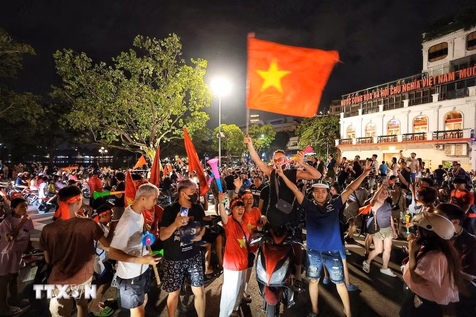 Du khách nước ngoài hòa cùng niềm vui chiến thắng của đội tuyển Việt Nam. (Ảnh: Phạm Tuấn Anh/TTXVN)