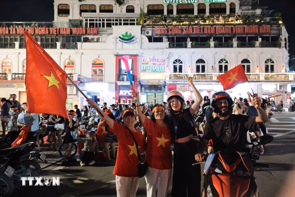 Du khách nước ngoài hòa cùng niềm vui chiến thắng của đội tuyển Việt Nam. (Ảnh: Phạm Tuấn Anh/TTXVN)
