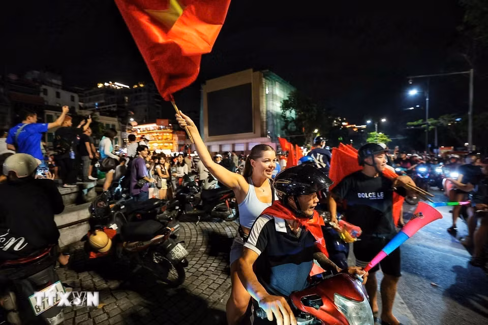 Du khách nước ngoài hòa cùng niềm vui chiến thắng của đội tuyển Việt Nam. (Ảnh: Phạm Tuấn Anh/TTXVN)