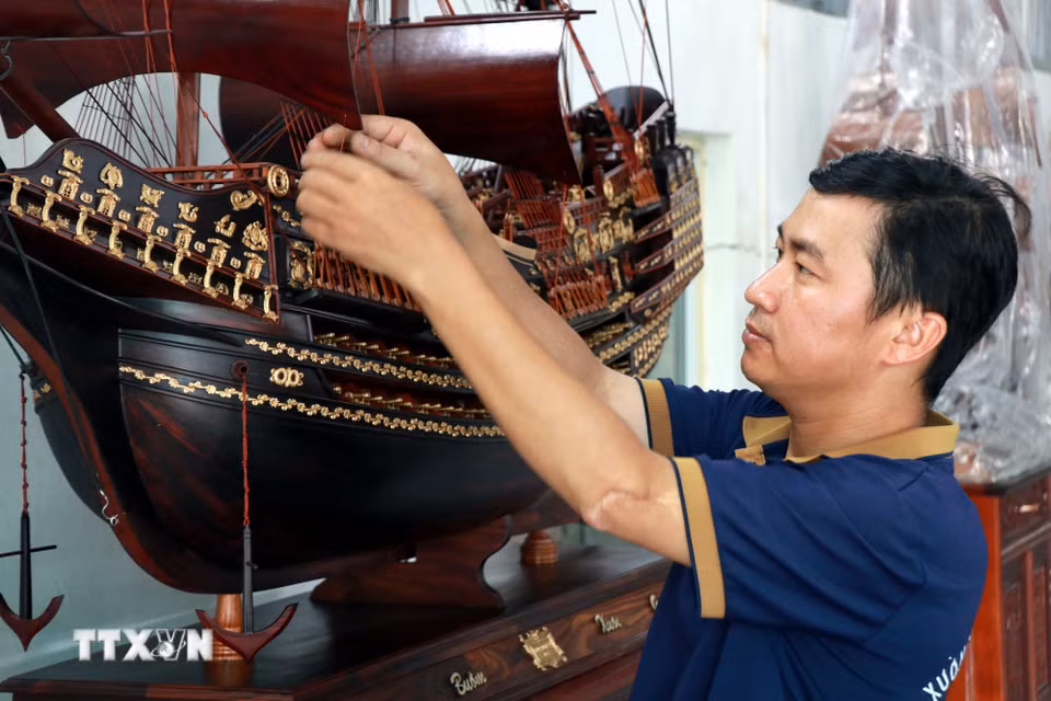 Anh Trần Văn Điệp, xã Cát Thành (Ninh Bình) căng chỉnh các dây buồm trên sản phẩm. (Ảnh: Nguyễn Lành/TTXVN)