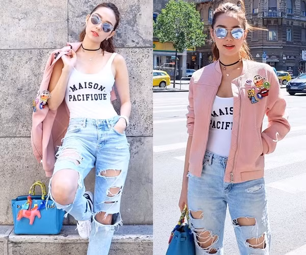 Cũng có mặt tại Budapest trong tuần vừa rồi, Minh Hằng ghi điểm tuyệt đối với người hâm mộ khi 'chơi trội' cùng bộ đồ phối theo công thức layer. Nữ diễn viên đa tài mix áo sát nách dáng ôm và quần jeans rách bụi phủi, bên ngoài là áo khoác màu hồng phấn. Cô càng sành điệu hơn khi điểm thêm cặp phụ kiện vòng cổ choker và kính mắt tráng gương hợp mốt.