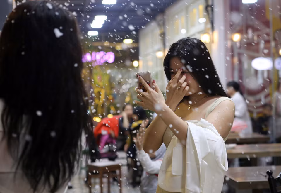 Tuyết rơi chậm rãi, lững thững bay giữa không gian dưới những ánh đèn đủ màu sắc càng trở nên lung linh, đẹp lạ mắt. (Ảnh: Trần Lê Lâm/Vietnam+)