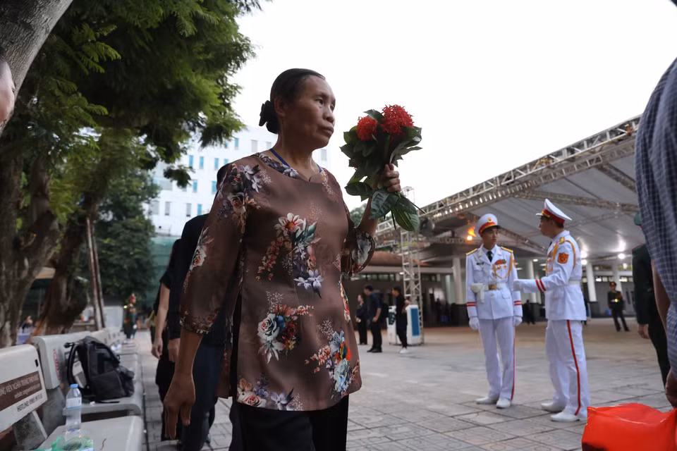 Ai nấy giữ trật tự ở khu vực Nhà tang lễ Quốc gia. Người mang theo hoa, cờ rủ. người mang theo di ảnh Tổng Bí thư. (Ảnh: Minh Sơn/Vietnam+)