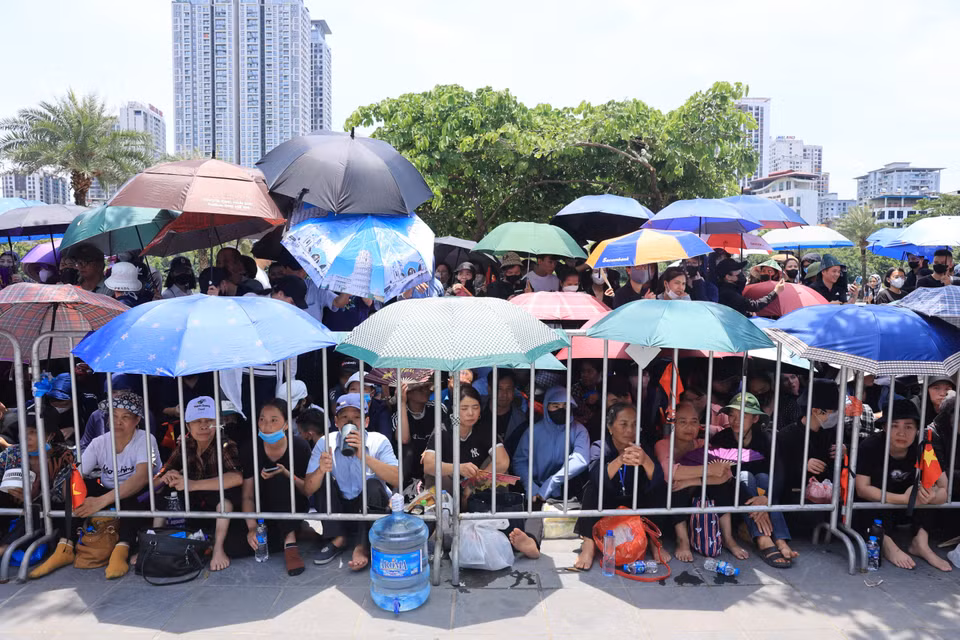 Khoảng 12h trưa, dù nhiệt độ ngoài trời hơn 40 độ C nhưng người dân đã đến rất đông để chờ tiễn Tổng Bí thư. (Ảnh: Hoài Nam/Vietnam+)