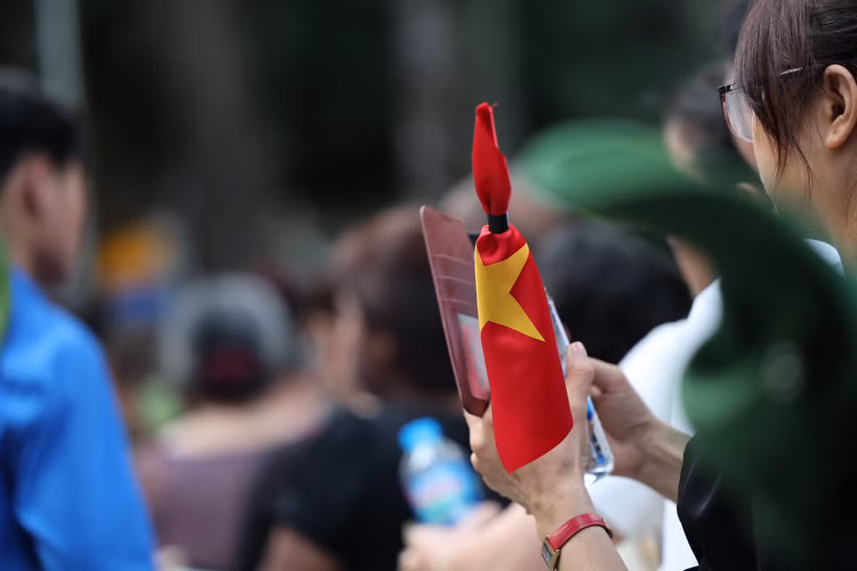 Nhiều bạn trẻ mang theo cờ rủ, lặng lẽ xếp hàng. (Ảnh: Minh Sơn/Vietnam+)