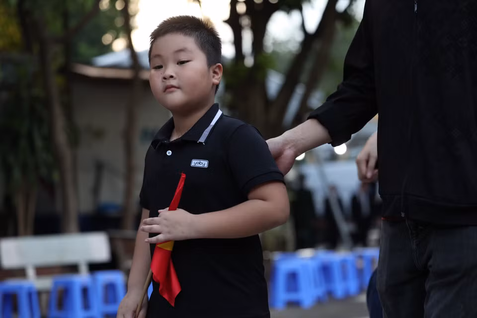 Có những cháu bé cũng trật tự, nghiêm trang theo ông bà, cha mẹ vào viếng. (Ảnh: Minh Sơn/Vietnam+)