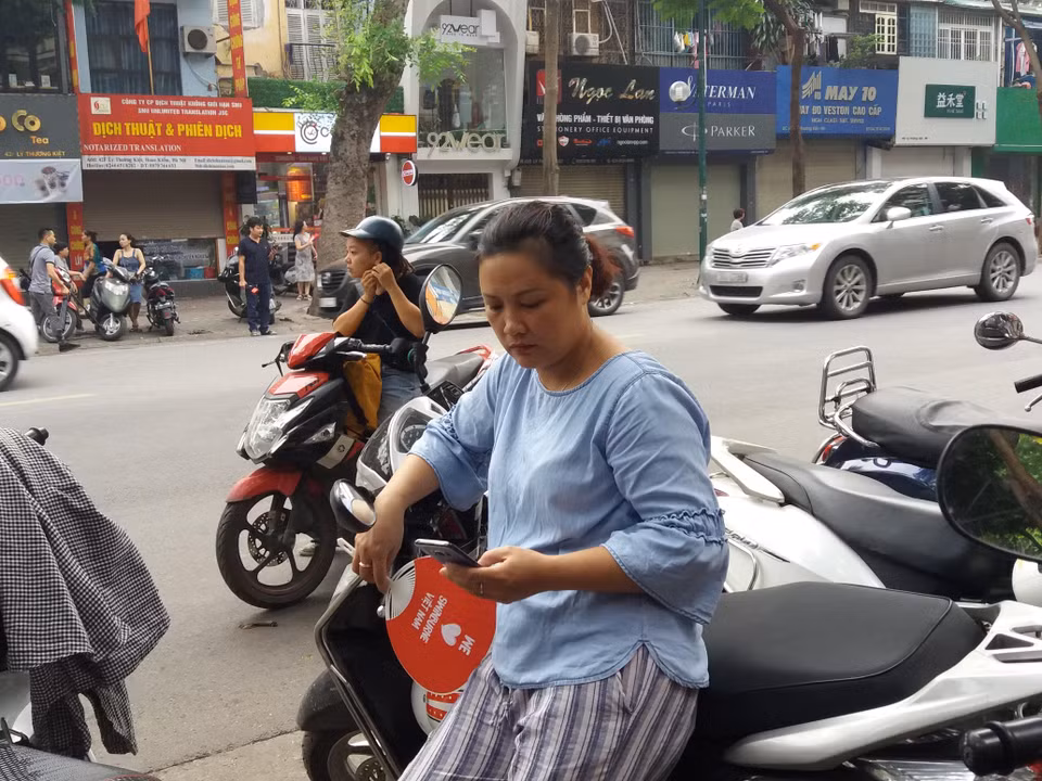 Phía bên ngoài cổng trường, các bậc phụ huynh bắt đầu nhìn đồng hồ và ngóng chờ đến hết giờ thi. (Ảnh: PM/Vietnam+)