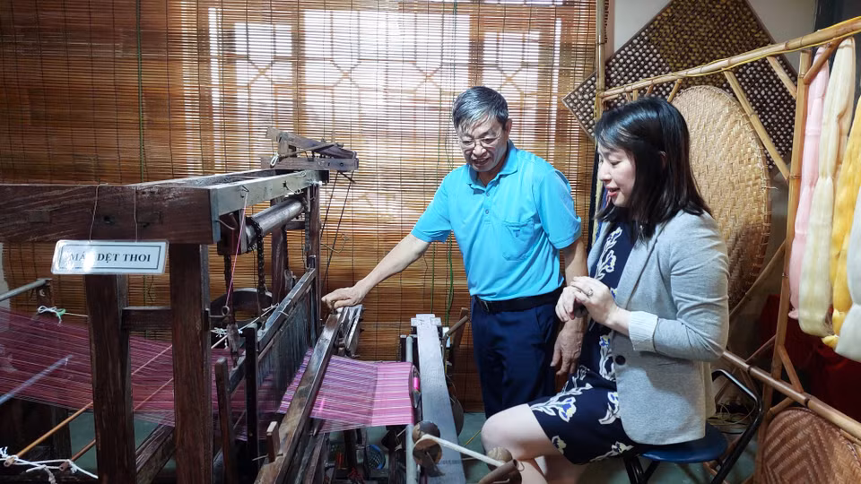 Nghệ nhân tại Trung tâm Nghiên cứu Dâu tằm tơ Trung ương hướng dẫn khách tham quan sử dụng máy dệt thoi. (Ảnh: Minh Thu/Vietnam+)