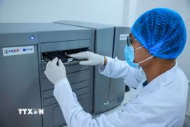 Kỹ thuật viên thực hiện xét nghiệm ADN thân nhân liệt sỹ trên máy microarray GeneTitan thể mô có thể phân tích hàng nghìn mẫu mô cùng lúc để tìm đột biến di truyền hoặc mức độ hoạt động của gene. (Ảnh: Hoàng Hiếu/TTXVN)