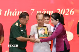 Phút nghẹn ngào của thân nhân liệt sỹ đón nhận di ảnh liệt sỹ đã được phục dựng. (Ảnh: Xuân Khu/TTXVN)