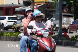 Người dân mặc đồ bảo hộ chống nắng nóng gay gắt. (Ảnh: Nguyên Lý/TTXVN)
