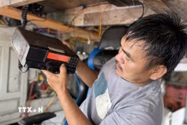 Ngư dân kiểm tra thiết bị giám sát hành trình trên biển trước khi ra khơi đánh bắt thủy sản. (Ảnh: Tường Quân/TTXVN)