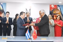 Bộ trưởng Nguyễn Hải Ninh và Bộ trưởng Oscar Manuel Silvera Martínez trao đổi kiện sau lễ ký. (Ảnh: Việt Hùng/TTXVN)