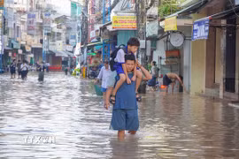Một học sinh được người thân cõng đến trường do đường Bùi Hữu Nghĩa (phường Bình Thủy) bị ngập ngày 8/10. (Ảnh: Thanh Liêm/TTXVN)