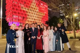 Cán bộ Tổng lãnh sự quán Việt Nam tại Perth chụp ảnh lưu niệm với hình ảnh Quốc kỳ Việt Nam được thắp sáng trên Tòa thị chính Perth. (Ảnh: TTXVN phát)