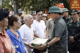 Phó Thủ tướng Trần Hồng Hà tặng quà các hộ bị ngập hoàn toàn. (Ảnh: Chu Hiệu/TTXVN)