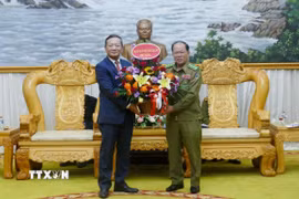 Đại sứ Việt Nam tại Lào Nguyễn Minh Tâm tặng hoa chúc mừng Bộ Công an Lào nhân dịp Kỷ niệm 50 năm Quốc khánh Lào và 105 Ngày sinh Chủ tịch Kaysone Phonvihane. (Ảnh: Xuân Tú/TTXVN)