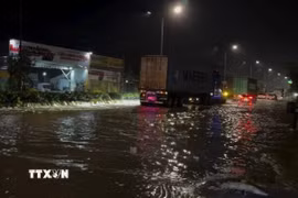 Nước dâng nhanh, chảy xiết qua đường ĐT747B, gần cầu Khánh Vân, phường Tân Hiệp, Thành phố Hồ Chí Minh, rạng sáng 6/10. (Ảnh: TTXVN phát)