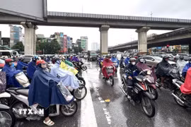 Người dân vất vả di chuyển trong điều kiện thời tiết không thuận lợi và giao thông ùn tắc tại ngã tư Nguyễn Xiển-Nguyễn Trãi. (Ảnh: Quốc Lũy/TTXVN)