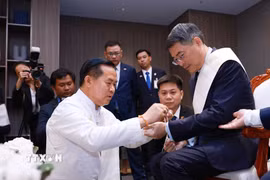 Thủ tướng Lê Minh Hưng thực hiện nghi thức buộc chỉ cổ tay truyền thống của Lào. (Ảnh: Dương Giang/TTXVN)