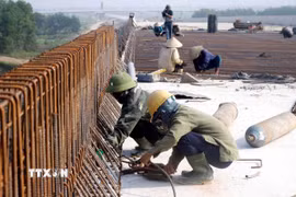 Công nhân Tổng công ty 319 Bộ Quốc phòng thi công trên cây cầu bắc qua sông Già, huyện Can Lộc (Hà Tĩnh). (Ảnh: Công Tường/TTXVN)
