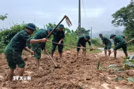 Các cán bộ, chiến sỹ Đồn Biên phòng Ba Nang khẩn trương dọn dẹp, khắc phục các điểm sạt lở do mưa lớn. (Ảnh: TTXVN phát)
