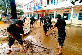 Cán bộ, chiến sỹ Cục Hậu cần - Kỹ thuật Quân khu 5 hỗ trợ một trong tiểu học trên địa bàn xã Nông Sơn dọn bùn non sau khi nước rút. (Ảnh: PV/Vietnam+)