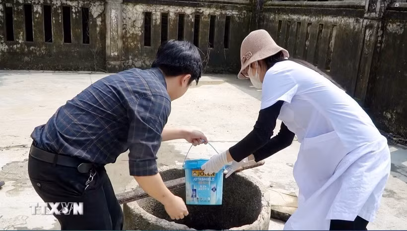 Cán bộ y tế hỗ trợ người dân xử lý nguồn nước sinh hoạt sau lũ. (Ảnh: TTXVN phát)
