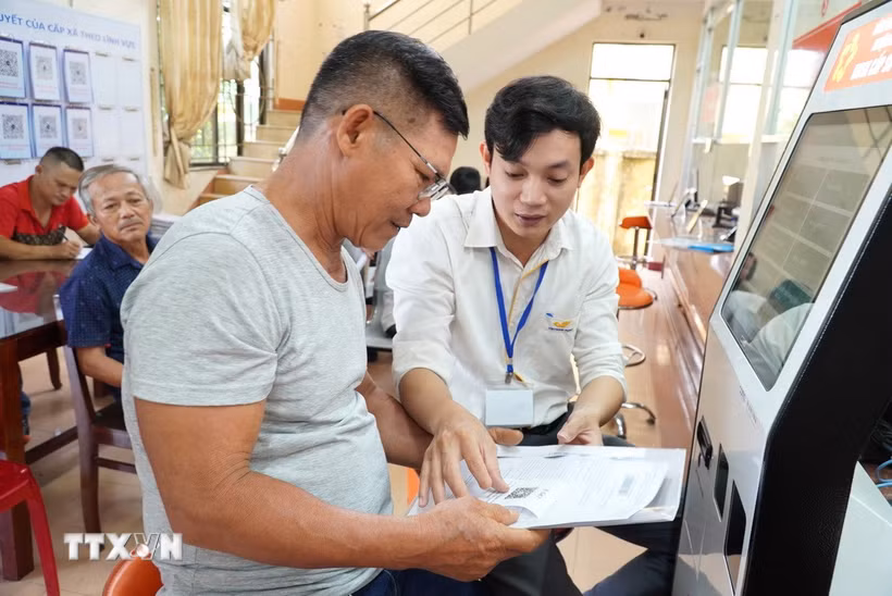 Cán bộ hướng dẫn người dân thực hiện thủ tục hành chính tại Quảng Ngãi. (Ảnh: Đinh Hương/TTXVN)