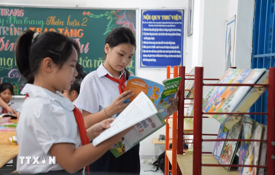 Học sinh trường Tiểu học Tây Nha Trang chọn sách tham khảo trong tủ sách Đinh Hữu Dư. (Ảnh: Nguyễn Dũng/TTXVN)